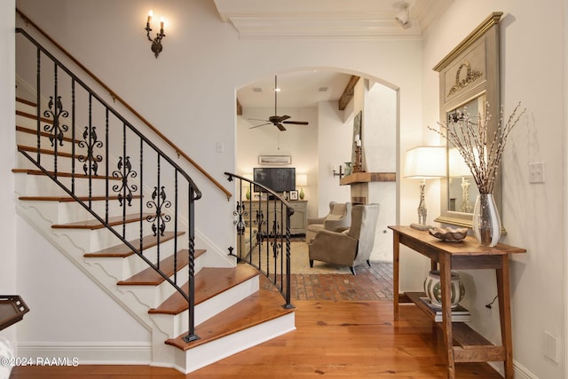 stairway with ceiling fan, hardwood / wood-style flooring, and ornamental molding