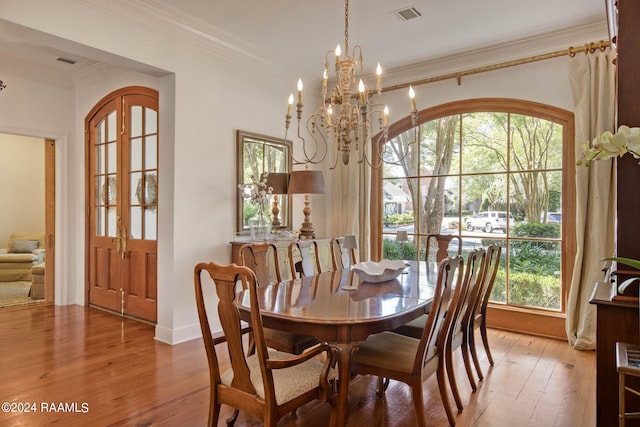 dining area featuring a notable chandelier, a healthy amount of sunlight, crown molding, and hardwood / wood-style floors