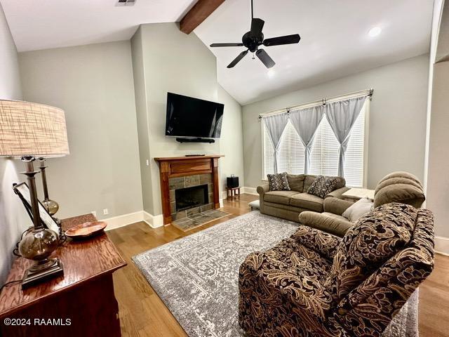 living room featuring a fireplace, wood-type flooring, vaulted ceiling with beams, and ceiling fan