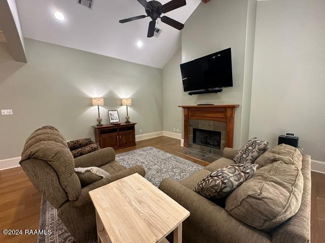 living room with hardwood / wood-style flooring, high vaulted ceiling, ceiling fan, and a tiled fireplace