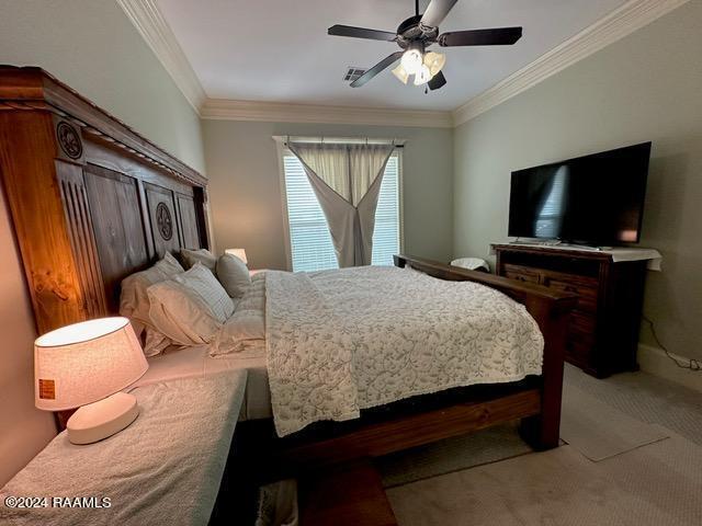 bedroom featuring ornamental molding, carpet flooring, visible vents, and a ceiling fan