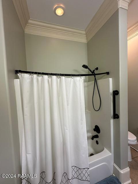 bathroom featuring toilet, ornamental molding, and shower / tub combo with curtain