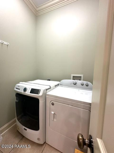 clothes washing area with washer and clothes dryer, light tile patterned floors, and crown molding