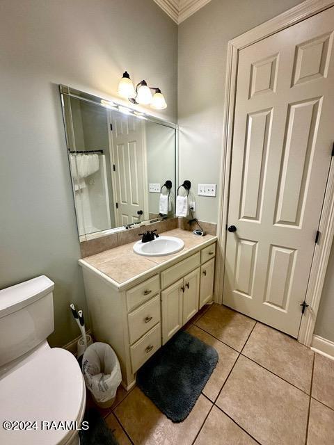 bathroom with toilet, vanity, tile patterned floors, and ornamental molding