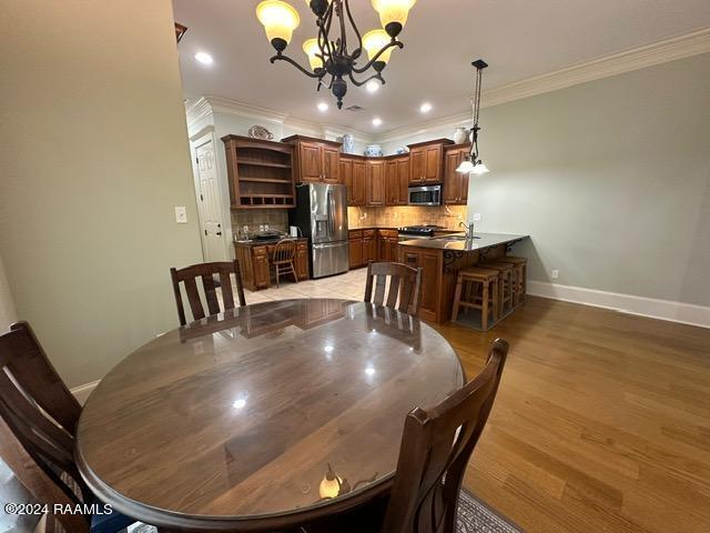 dining room with a chandelier, recessed lighting, light wood-style floors, baseboards, and crown molding