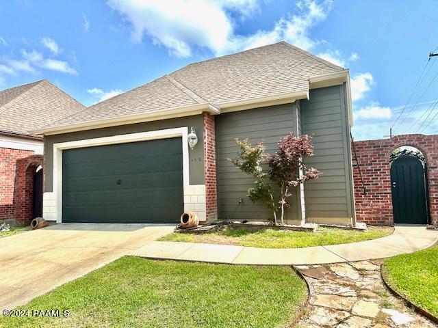 view of front of house featuring driveway, roof with shingles, and an attached garage