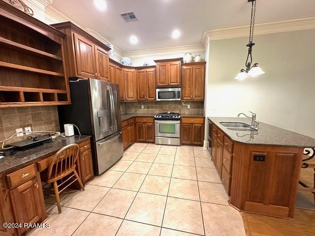 kitchen with tasteful backsplash, stainless steel appliances, sink, decorative light fixtures, and light tile patterned flooring