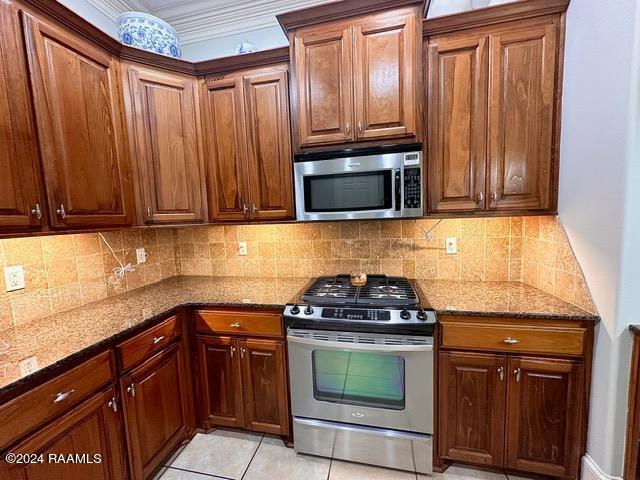 kitchen with light tile patterned floors, stainless steel appliances, tasteful backsplash, and dark stone countertops