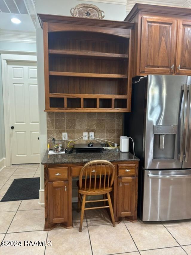 kitchen with light tile patterned flooring, crown molding, stainless steel refrigerator with ice dispenser, and tasteful backsplash