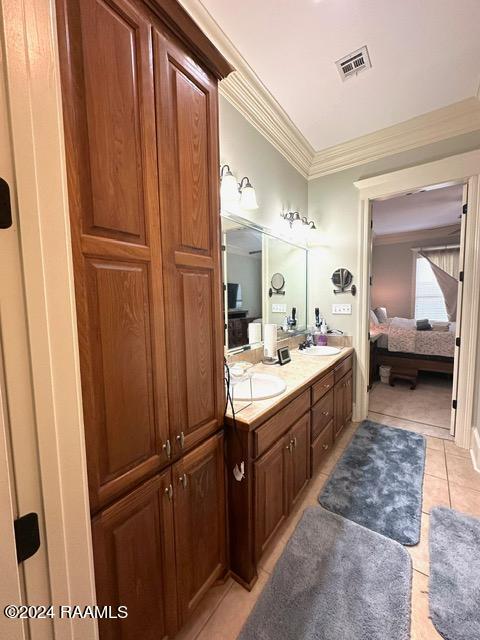 bathroom featuring tile patterned flooring, vanity, and crown molding