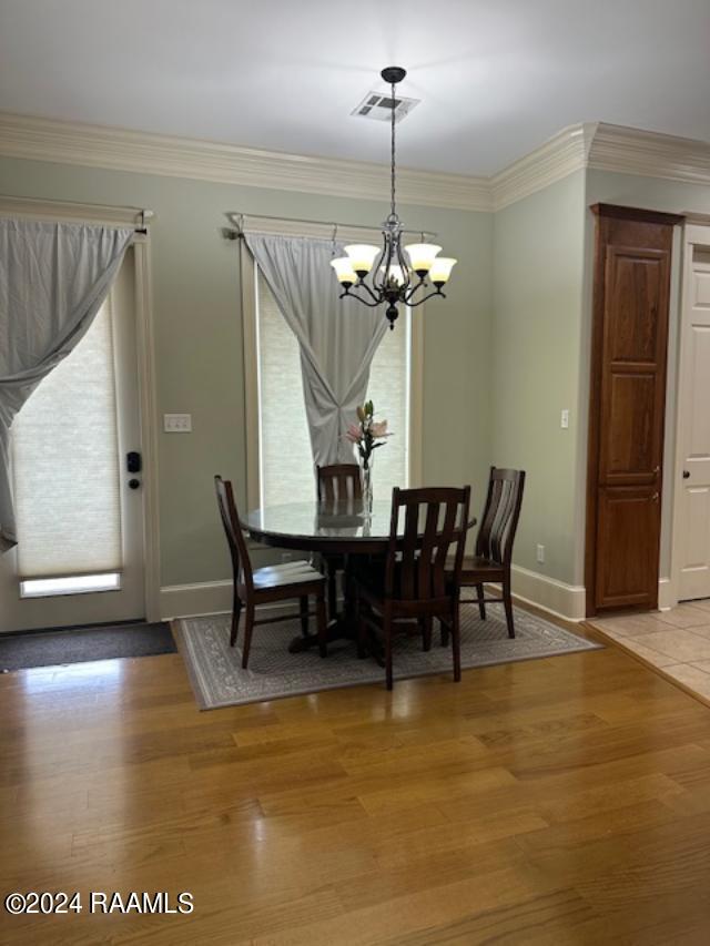 dining space featuring a chandelier, light hardwood / wood-style floors, and ornamental molding