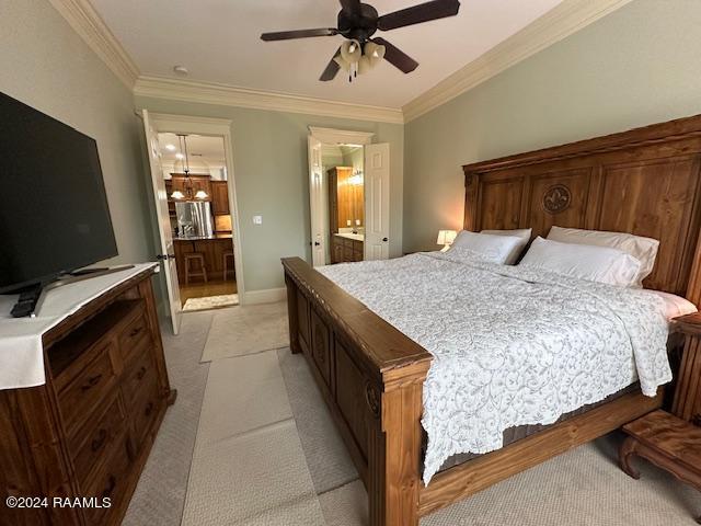 bedroom featuring ceiling fan, light colored carpet, crown molding, and ensuite bath