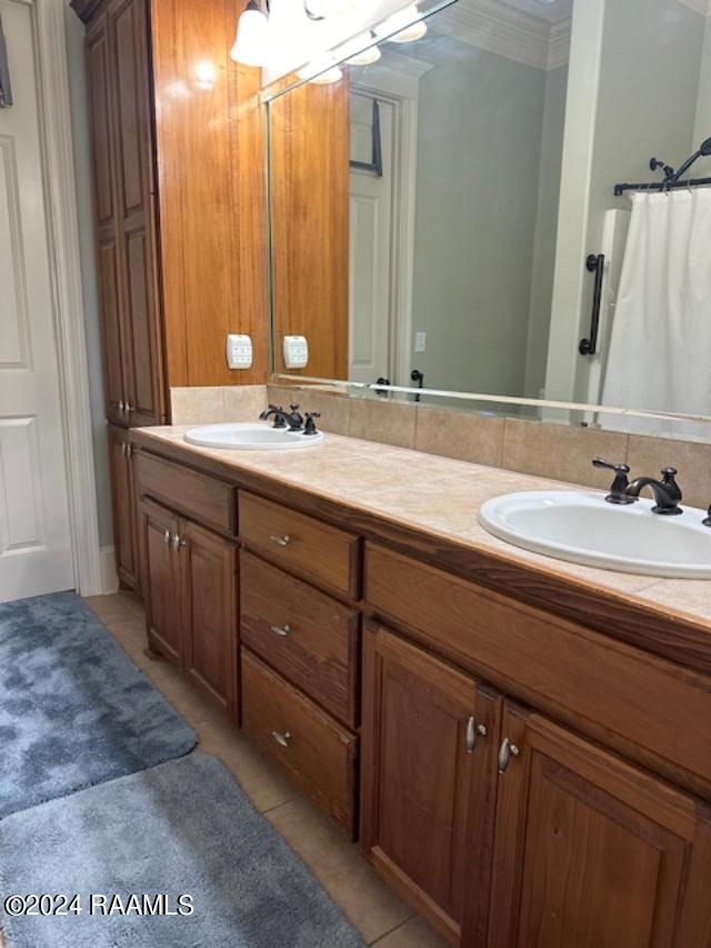 bathroom with ornamental molding, double vanity, a sink, and tile patterned floors