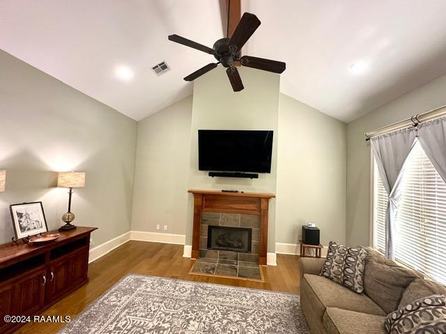 living room featuring a tile fireplace, lofted ceiling, and hardwood / wood-style flooring