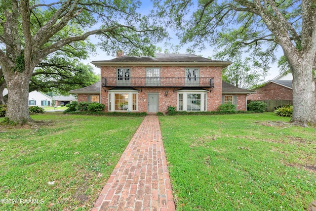 view of front of house featuring a balcony and a front yard