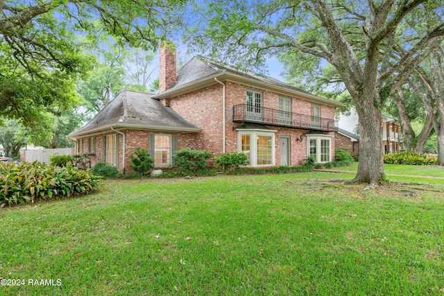 view of property with a balcony and a front yard