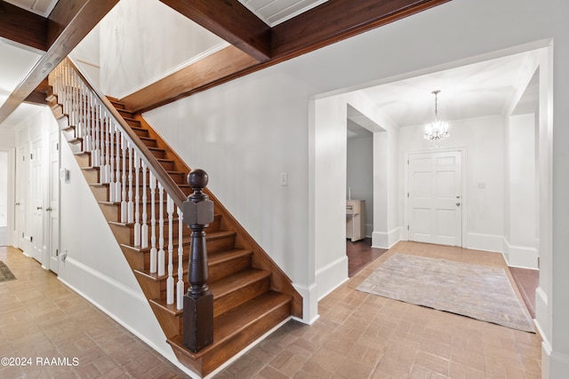 entrance foyer with tile flooring, beamed ceiling, and a notable chandelier