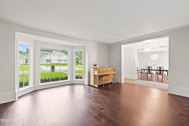 spare room featuring dark hardwood / wood-style flooring, an inviting chandelier, and ornamental molding