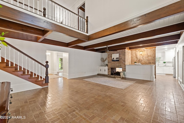 unfurnished living room featuring beamed ceiling, brick wall, and a fireplace