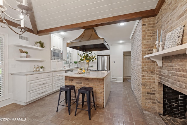 kitchen with custom exhaust hood, a kitchen island, white cabinets, stainless steel appliances, and light stone countertops