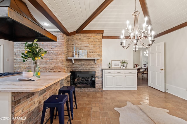 living room with a brick fireplace, crown molding, brick wall, beam ceiling, and a chandelier