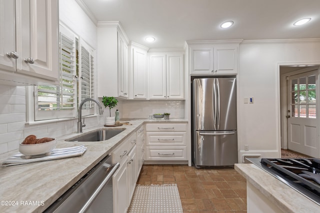 kitchen with tasteful backsplash, stainless steel appliances, white cabinetry, and sink