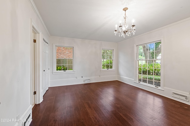 empty room featuring a notable chandelier, hardwood / wood-style flooring, and ornamental molding