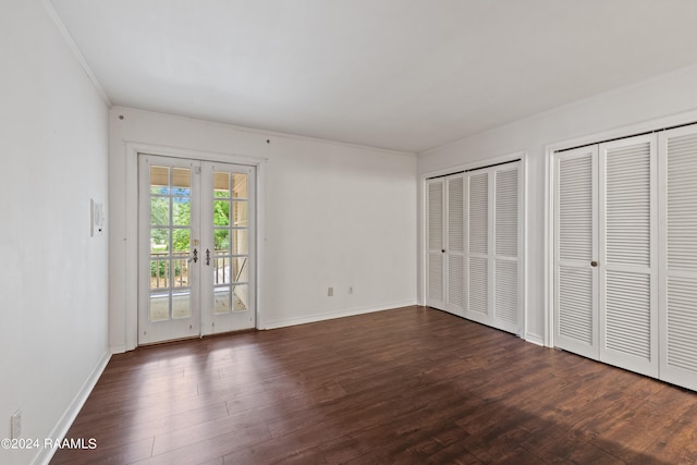 unfurnished bedroom with access to outside, french doors, dark wood-type flooring, ornamental molding, and two closets