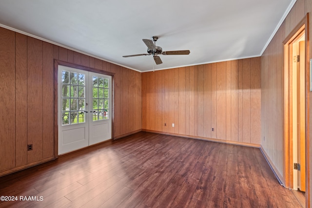 spare room featuring dark hardwood / wood-style floors, french doors, wooden walls, and ornamental molding