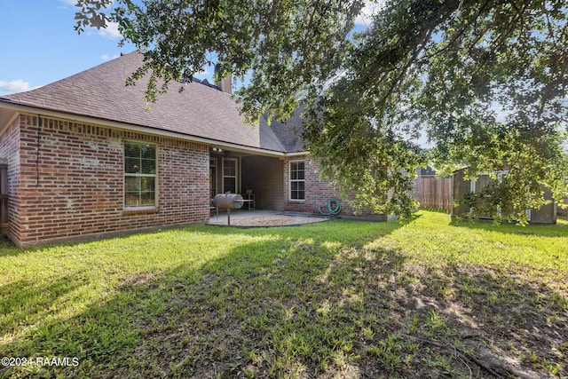 rear view of property featuring a lawn and a patio