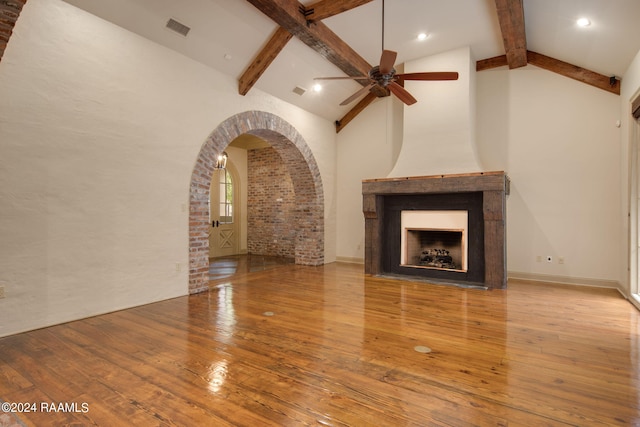 unfurnished living room with ceiling fan, beam ceiling, high vaulted ceiling, a fireplace, and light hardwood / wood-style floors