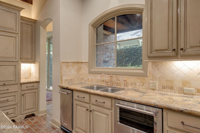 kitchen featuring backsplash, wine cooler, light stone counters, and sink