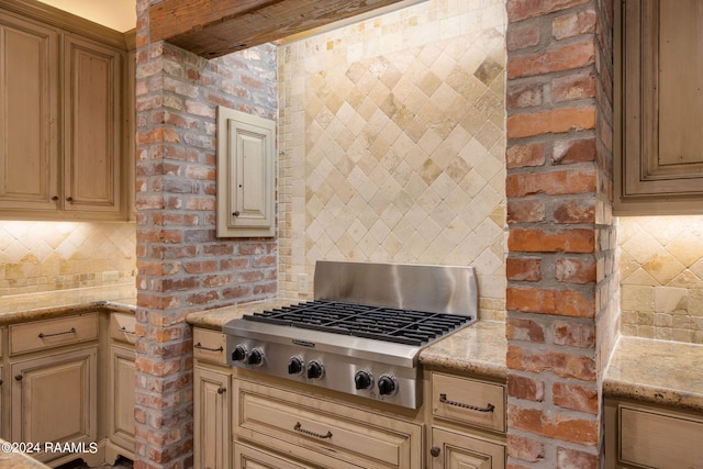 kitchen featuring stainless steel gas stovetop, brick wall, and tasteful backsplash