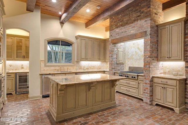 kitchen featuring tasteful backsplash, stainless steel appliances, a kitchen island, beamed ceiling, and wine cooler