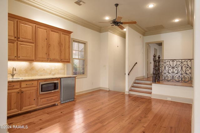 kitchen with sink, ceiling fan, ornamental molding, appliances with stainless steel finishes, and light hardwood / wood-style floors