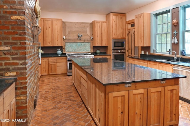 kitchen with dark stone countertops, appliances with stainless steel finishes, decorative backsplash, a kitchen island, and sink