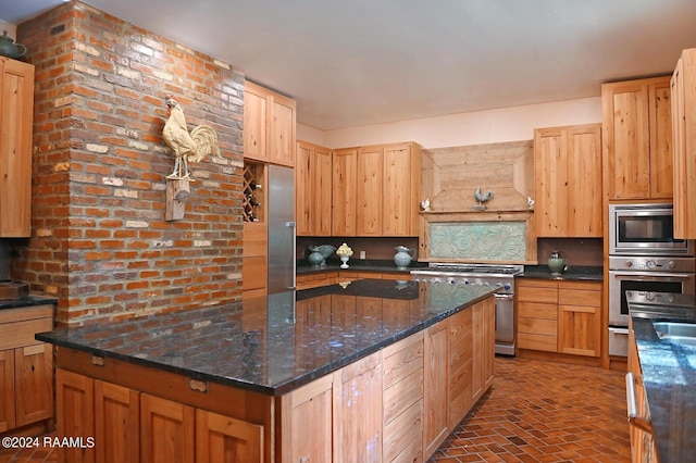 kitchen featuring dark stone countertops, appliances with stainless steel finishes, premium range hood, light brown cabinetry, and backsplash