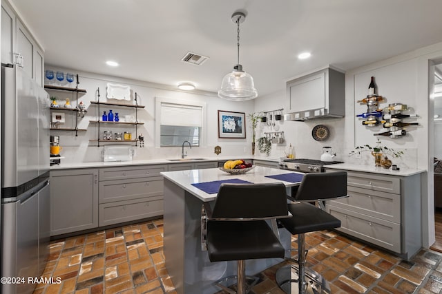 kitchen with stainless steel fridge, decorative light fixtures, backsplash, gray cabinetry, and sink