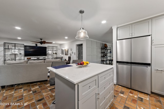 kitchen with stainless steel fridge, a kitchen island, gray cabinets, pendant lighting, and ceiling fan