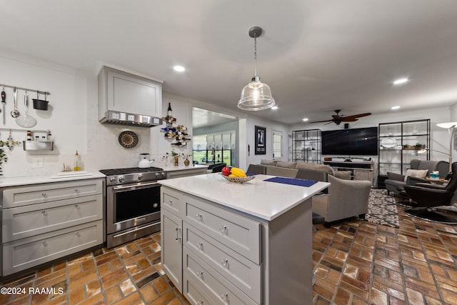 kitchen featuring a kitchen island, gray cabinetry, stainless steel range with gas cooktop, decorative light fixtures, and ceiling fan