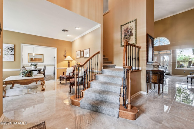 stairway featuring marble finish floor, baseboards, a high ceiling, and ornamental molding