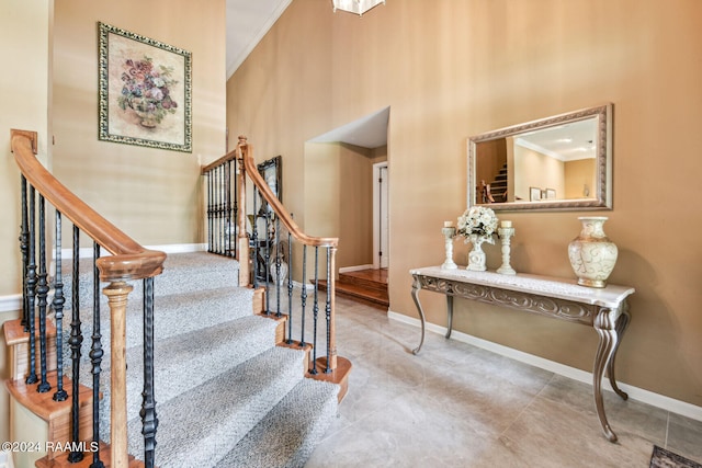 stairway with a high ceiling, tile flooring, and crown molding