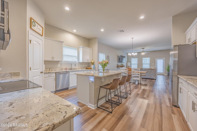 kitchen with appliances with stainless steel finishes, light hardwood / wood-style flooring, a center island, and white cabinets