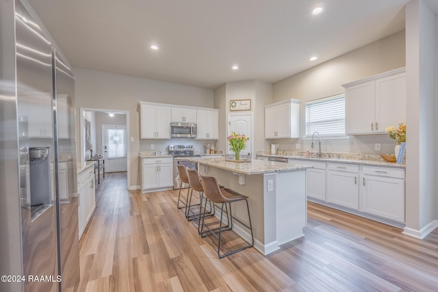 kitchen featuring a kitchen island, stainless steel appliances, light hardwood / wood-style floors, and white cabinetry