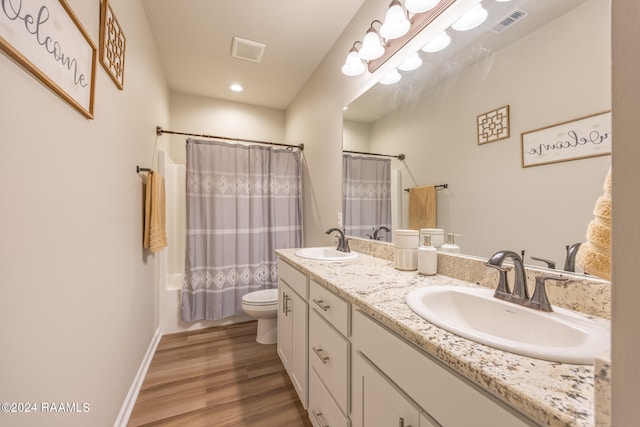 bathroom featuring hardwood / wood-style floors, vanity with extensive cabinet space, toilet, and double sink