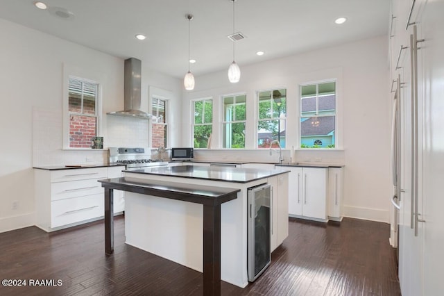 kitchen featuring wall chimney range hood, tasteful backsplash, a kitchen island, and dark wood-type flooring