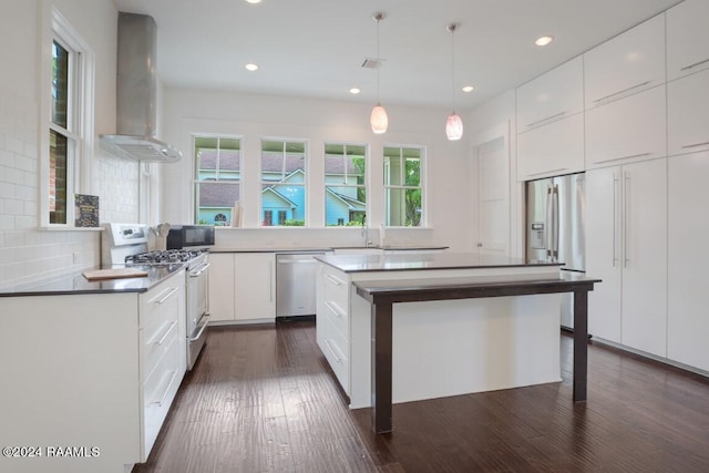 kitchen featuring a kitchen island, backsplash, stainless steel appliances, dark hardwood / wood-style floors, and wall chimney exhaust hood