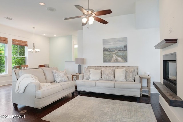 living room with ceiling fan with notable chandelier and dark hardwood / wood-style flooring