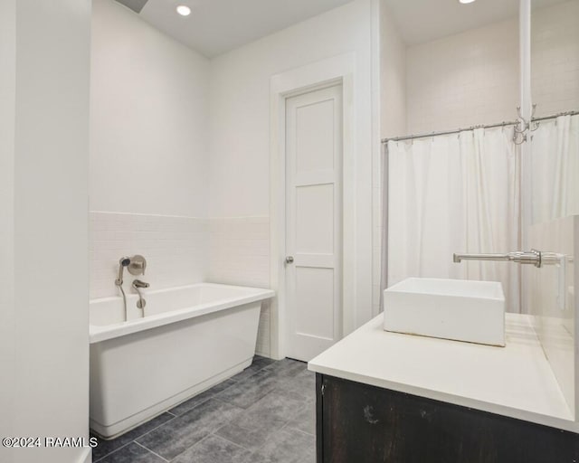 bathroom with a washtub, vanity, and tile floors