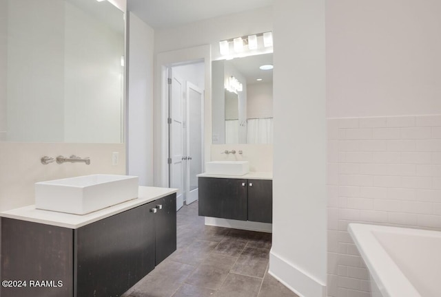 bathroom with tile walls, a bath to relax in, vanity, and tile flooring